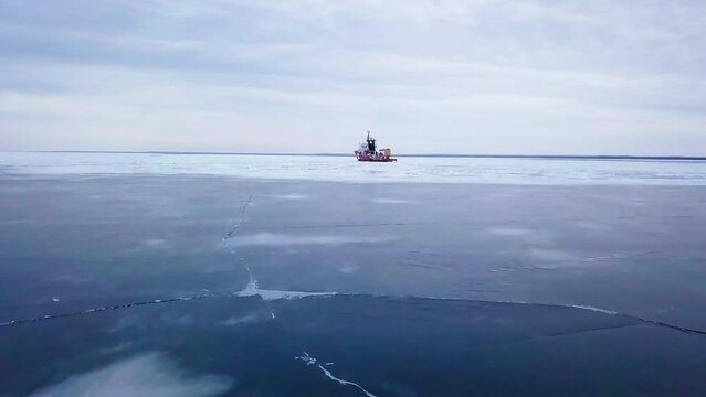 Aerial Forward Scenic Shot Of Nautical Vessel Moored On Ice Under Cloudy Sky - Marquette, Michigan