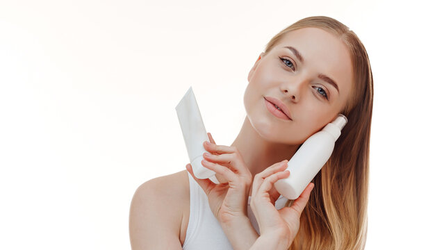 Beautiful blonde girl with a bottle of shampoos in hands. Girl with shiny and long hair. Woman long hair. Woman hold bottle shampoo and conditioner. Woman holding shampoo bottle.
