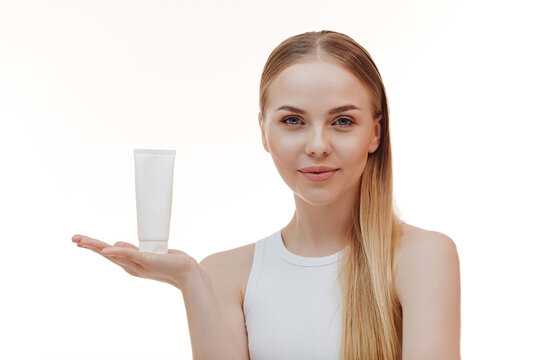 Beauty blonde holds a jar of shampoo or conditioner in her hands. Long blonde hair.