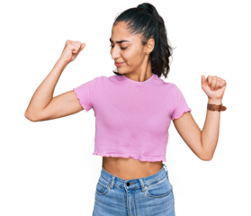 Hispanic teenager girl with dental braces wearing casual clothes showing arms muscles smiling proud. fitness concept.