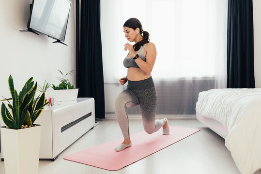 Sporty Plus Size Woman In Sportswear Working Out At Home, Doing Plank On Yoga Mat In Front Of Open Laptop, Repeating Instructions By Professional Fitness Trainer Watching Online Video Tutorial