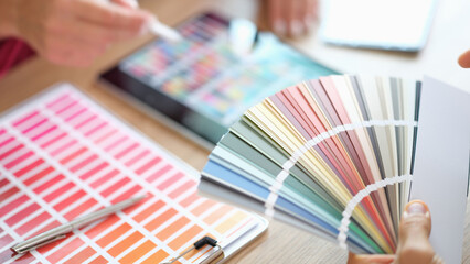 Designer holding fan of colourful paper samples in hand