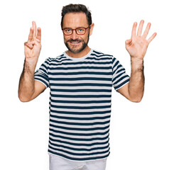 Naklejka premium Middle age man wearing casual clothes and glasses showing and pointing up with fingers number eight while smiling confident and happy.