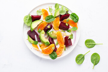 Light spring and summer salad with beets, oranges, avocados, spinach and micro leaves, white background. Balanced plant based  diet