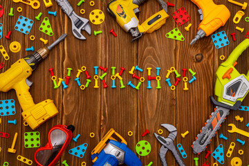 Toy tools, bolts and nuts with text WORKSHOP on wooden background