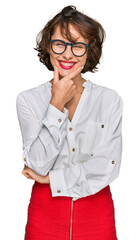 Young hispanic woman wearing business style and glasses looking confident at the camera smiling with crossed arms and hand raised on chin. thinking positive.