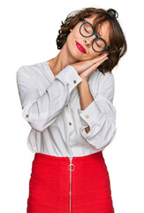 Young hispanic woman wearing business style and glasses sleeping tired dreaming and posing with hands together while smiling with closed eyes.