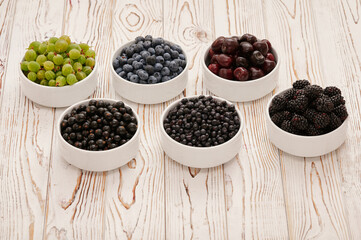 Fresh berries in six bowls on a wooden background. Fruit berry background.