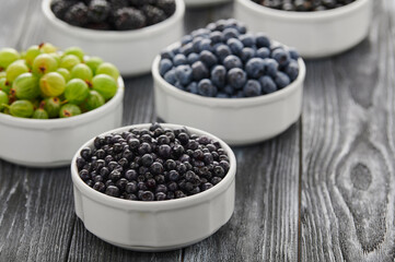 ripe wild berries blackberries, black currants and blueberries in bowls