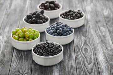 Fresh berries in six bowls on a wooden background. Fruit berry background.