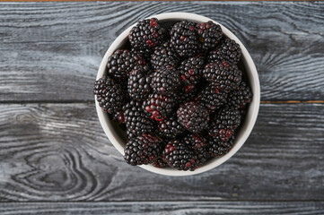 Ripe blackberries in a plate on a dark wooden table