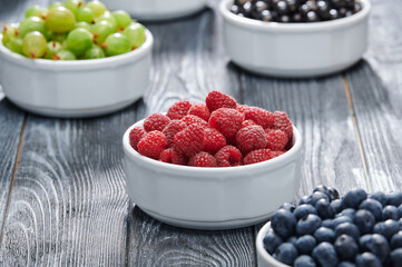 raspberries in a white bowl, blueberries, gooseberries, raspberries, blackcurrants, close-up shot