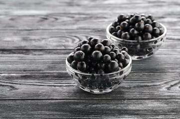 ripe black currants in bowls on a wooden table