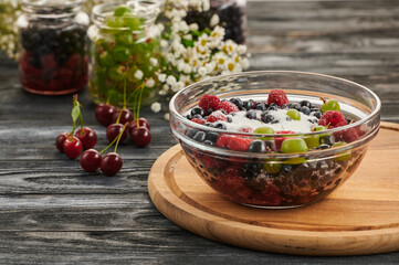 Preservation in jars with berries on a wooden table, a mix of blueberries, gooseberries, raspberries, black currants