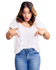 Obraz premium Young beautiful caucasian woman wearing casual white tshirt pointing down with fingers showing advertisement, surprised face and open mouth