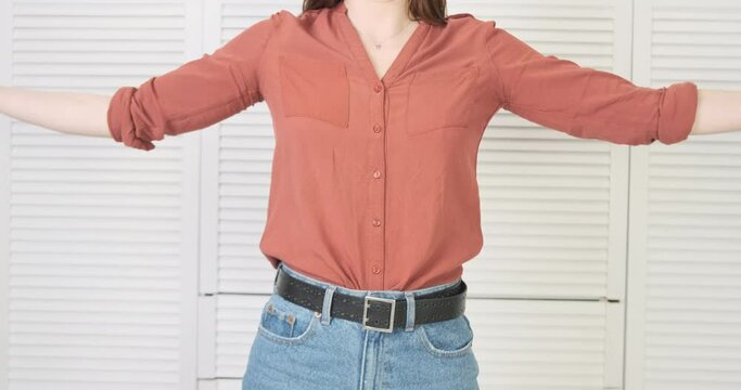 Woman holds a bunch of shoes in her armful. Spreads arms and shoes fall down. Front view. Concept of getting rid of unnecessary things, the treatment of a shopaholic, freedom from addiction.