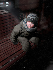 frightened little boy sitting on a bench at night