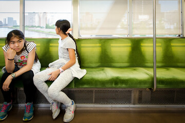 Two asian girls lying down on empty train seats in Tokyo Japan