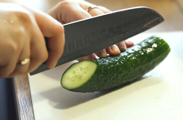 A little boy cuts a cucumber with a knife. © Dzmitry