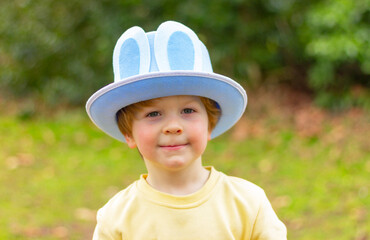 portrait of cute child boy in blue Easter hat with bunny ears on a natural background