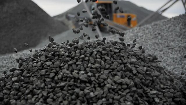 Small gravel grains fall on pile against driving backhoe at rock extraction quarry macro view. Natural resources digging