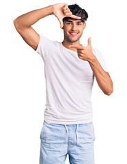 Young hispanic man wearing casual clothes smiling making frame with hands and fingers with happy face. creativity and photography concept.