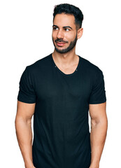 Hispanic man with beard wearing casual black t shirt smiling looking to the side and staring away thinking.