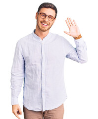 Handsome young man with bear wearing elegant business shirt and glasses waiving saying hello happy...