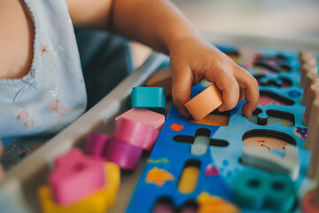 Close-up view of baby's hands playing in a puzzle made of colorful figurines. Education concept. Family activity concept. Happy family kid concept. Lifestyle