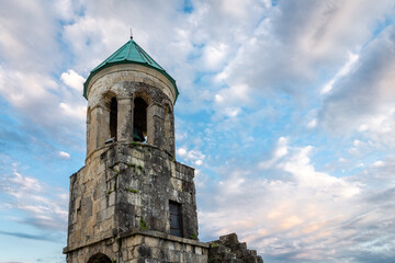 Belfry tower of Bagrati Cathedral (Kutaisi Cathedral), XI-century monastery, example of Georgian architecture with stone walls and turquoise dome against blue sky, Kutaisi, Georgia.