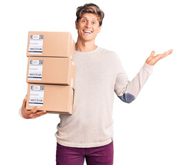 Young handsome man holding delivery package celebrating victory with happy smile and winner...