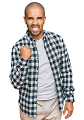 Fototapeta na wymiar Hispanic adult man wearing casual clothes angry and mad raising fist frustrated and furious while shouting with anger. rage and aggressive concept.
