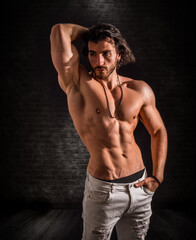 Fototapeta premium Confident, attractive shirtless muscular young man with open vest on