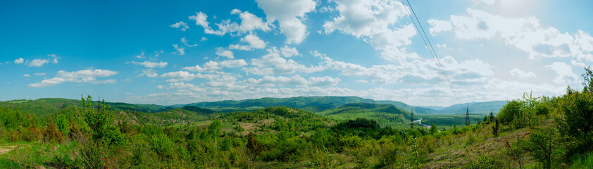Fototapeta na wymiar Panorama of the spring forest near the mountain town. Picturesque landscape of a sunny day.