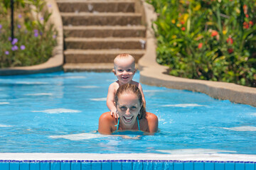 Portrait of boy having fun in pool with joyful mother. Healthy family lifestyle, water sports activity, baby swimming and diving underwater lessons with active parents on summer holidays with children