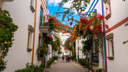 A narrow street full of colorful flowers. Puerto de Mogán