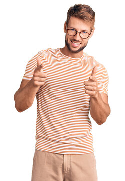 Young caucasian man wearing casual clothes and glasses pointing fingers to camera with happy and funny face. good energy and vibes.