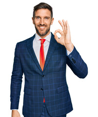 Handsome man with beard wearing business suit and tie smiling positive doing ok sign with hand and...