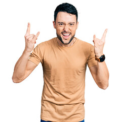 Naklejka premium Hispanic man with beard wearing casual t shirt shouting with crazy expression doing rock symbol with hands up. music star. heavy music concept.