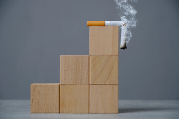 Top wooden ladder of cubes lies a broken, smoking cigarette.Concept World No Tobacco Day.