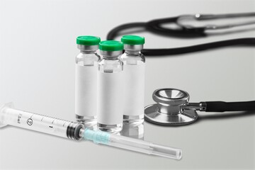 Bottles of medical vaccine vials with stethoscope on desk