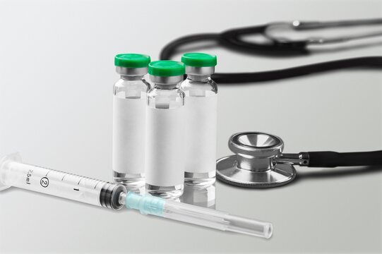 Bottles of medical vaccine vials with stethoscope on desk