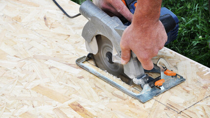 cutting OSB panels with an electric jigsaw, working hands