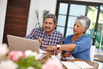 Budgeting with the help from technology. Shot of a senior couple working on their budget together at home.