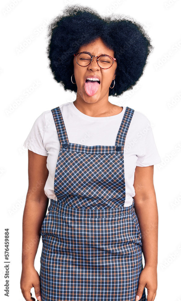 Poster young african american girl wearing casual clothes sticking tongue out happy with funny expression. 