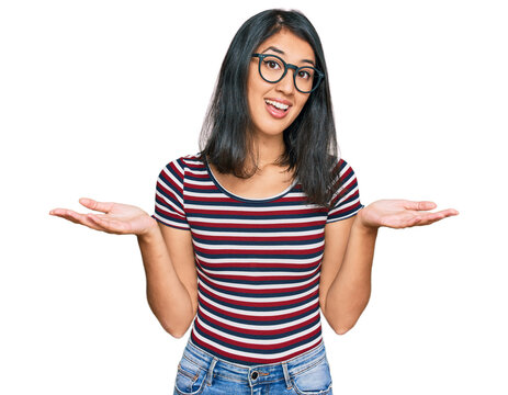 Beautiful asian young woman wearing casual clothes and glasses clueless and confused expression with arms and hands raised. doubt concept.