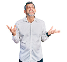 Fototapeta premium Middle age hispanic with grey hair wearing casual white shirt crazy and mad shouting and yelling with aggressive expression and arms raised. frustration concept.