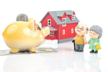 piggy bank for money and a model of a house with pensioners. buying a property. the concept of buying and selling houses and apartments