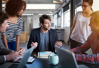 Fototapeta premium Explaining the finer points to the team. Shot of a group of coworkers brainstorming during a meeting.
