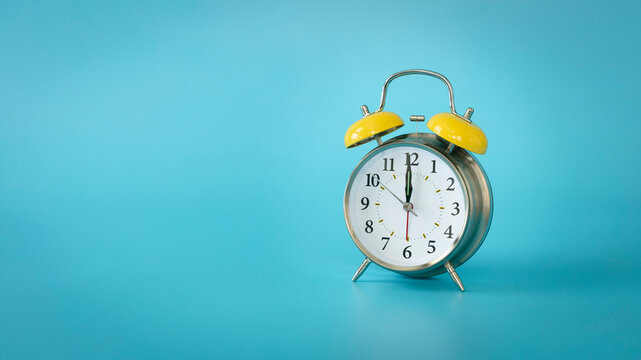 Retro silver alarm clock.  12:00, am, pm. Blue background.